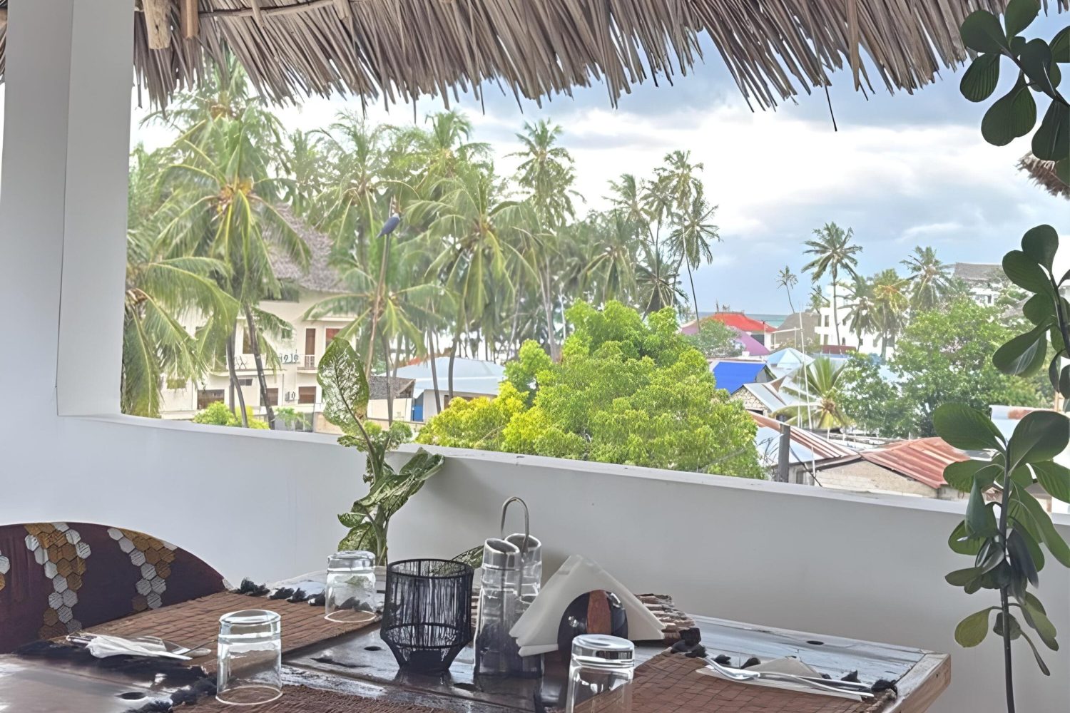 Shaded outdoor seating area with palm trees at ÔTALIA Hotel Restaurant