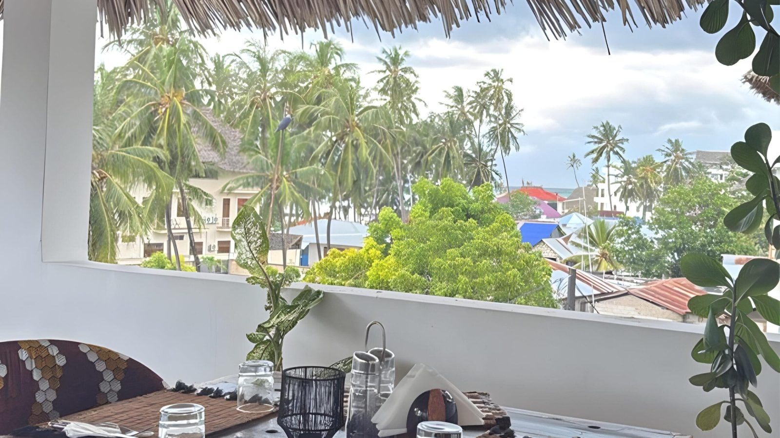 Shaded outdoor seating area with palm trees at ÔTALIA Hotel Restaurant